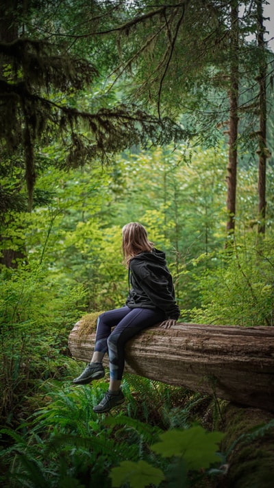 Dressed in a black long sleeve shirt and blue denim jeans women sitting on a brown wood
